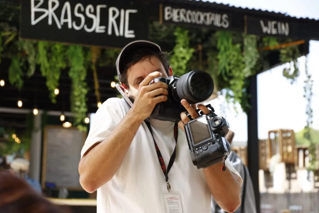 Alex Scharf fotografiert vor einer Brasserie in München