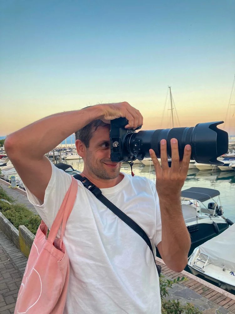 Fotograf Alex Scharf mit Teleobjektiv bei Sonnenuntergang